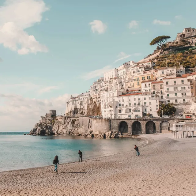 A pastel town stacked up a cliff above a beach